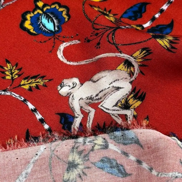 Tissu viscose singes et fleurs exotiques sur fond rouge