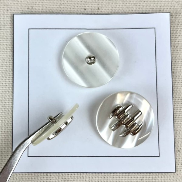 Bouton plastique blanc décoré argenté 25mm Bouton plastique blanc décoré argenté 25mm
