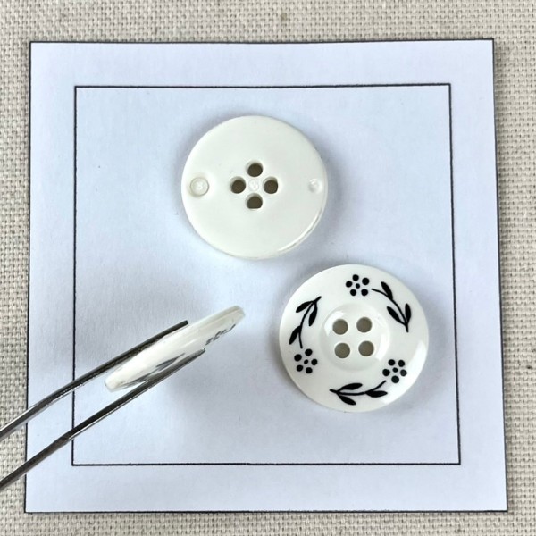 Bouton plastique fleurs dessinés blanc 22mm Bouton plastique fleurs dessinés blanc 22mm