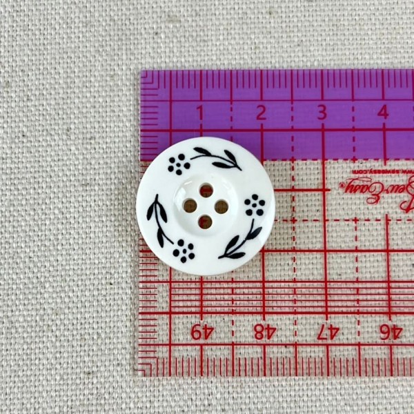 Bouton plastique fleurs dessinés blanc 22mm Bouton plastique fleurs dessinés blanc 22mm